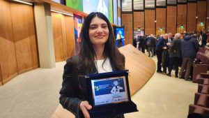 Martina Benedetti mostra la targa ricevuta per il premio Nazionale di Divulgazione Scientifica Giancarlo Dosi