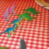 In copertina sulla tovaglia di una tavola apparecchiata piccoli dinosauri schierati come un esercito