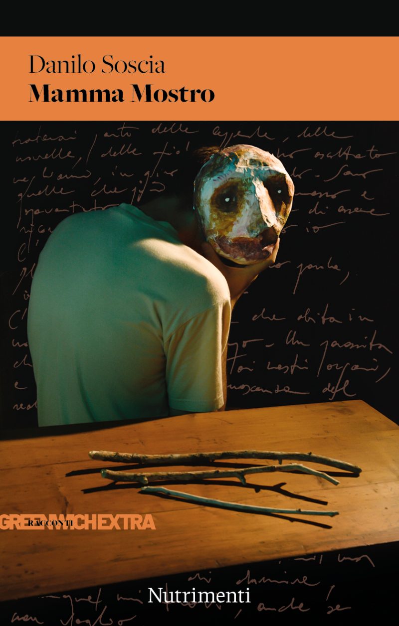 In copertina una figura di spalle con una maschera terrificante in volto davanto un tavolino con dei rametti sopra.